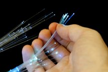 Bundle of optical fibers held in hand up close on black background